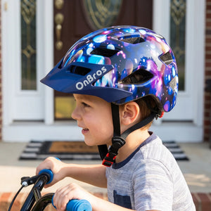 A little boy wearing a star blue helmet is riding a bicycle